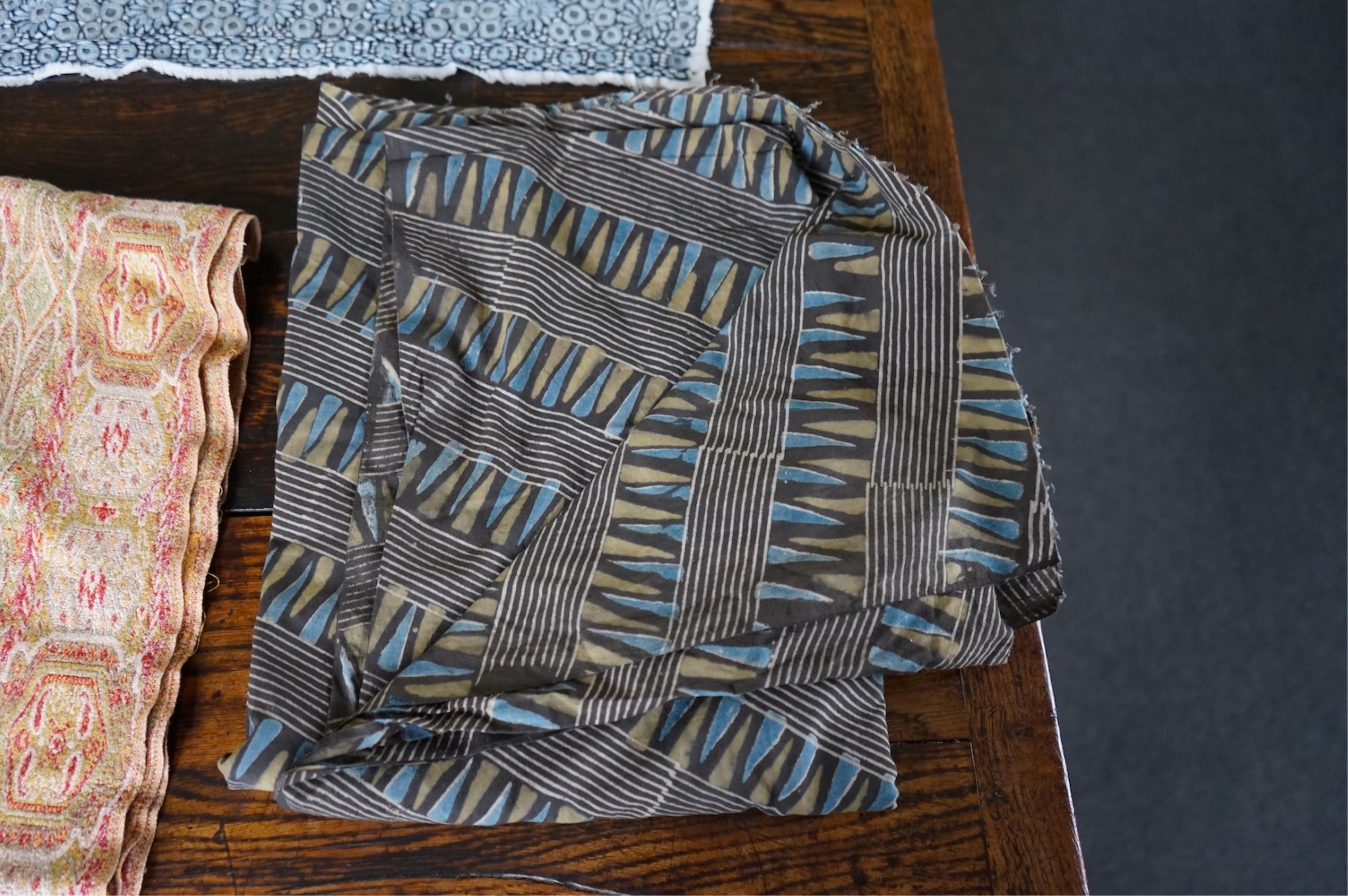 A long narrow length of grey Ikat woven fabric, a roll of Indian mirrored edging, a geometric batik printed length and a woven paisley ‘style’ tasselled stole. (4). Batik 392cm long x 108cm wide., Condition - good, all a